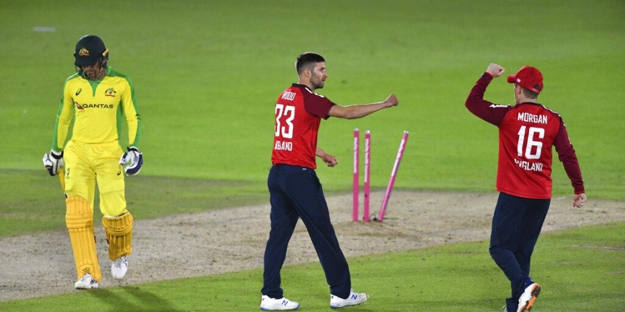 England's Mark Wood, center, celebrates with captain Eoin Morgan, right, the dismissal of Australia's Alex Carey, left, during the first Twenty20 cricket match.