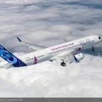 Airbus A320 aircraft parked at an airport while technicians prepare software updates following grounding due to potential solar radiation affecting flight control systems.