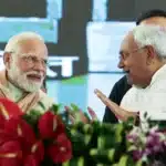 Prime Minister Narendra Modi and Chief Minister Nitish Kumar holding hands and greeting the crowd during the Bihar swearing-in ceremony.