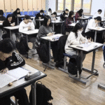 Students using AI-powered digital textbooks in a South Korean classroom, with teachers monitoring laptops and digital screens during lessons.