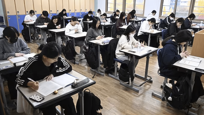 Students using AI-powered digital textbooks in a South Korean classroom, with teachers monitoring laptops and digital screens during lessons.